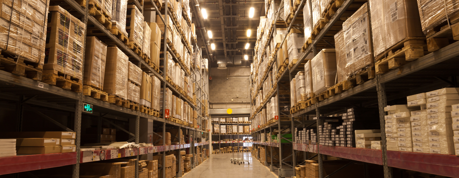 Large warehouse interior with stacked pallets and packaged goods on tall shelves, illustrating the importance of Warehouse Insurance for stock protection.