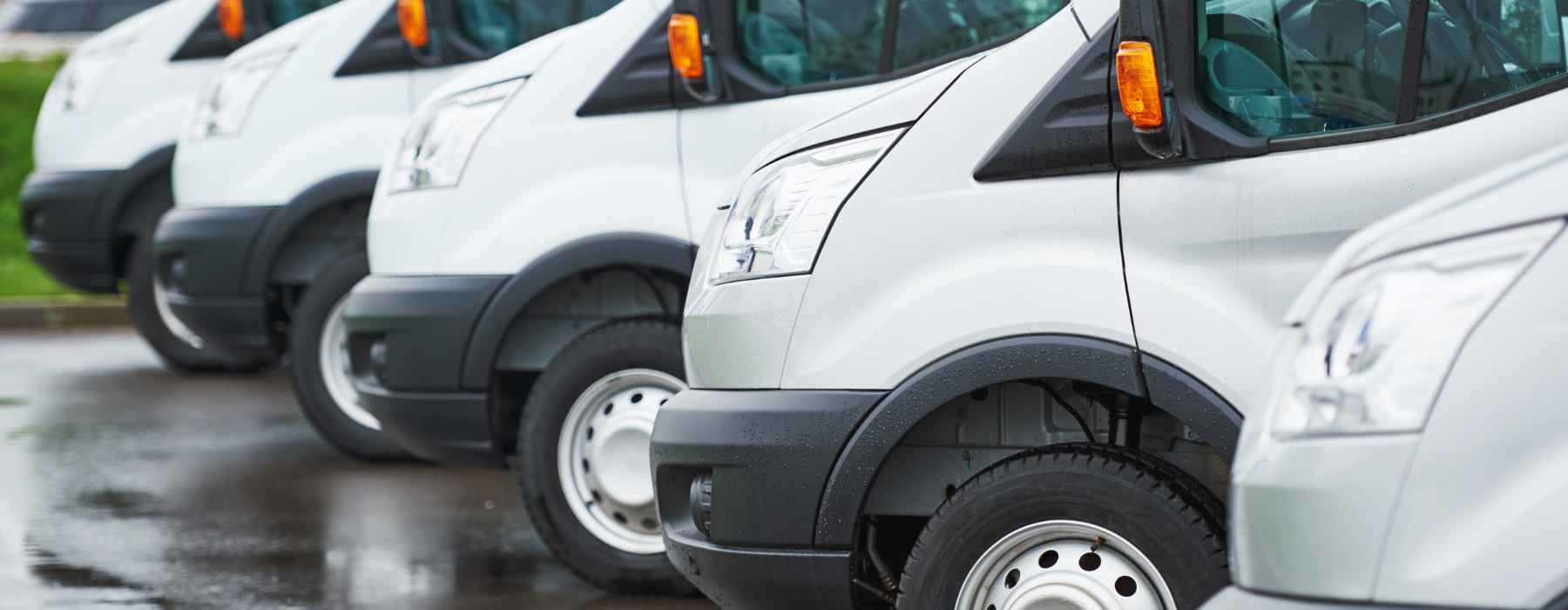 Row of white minibuses parked together, representing the protection and cost savings offered by Mini Bus Fleet Insurance for UK operators.
