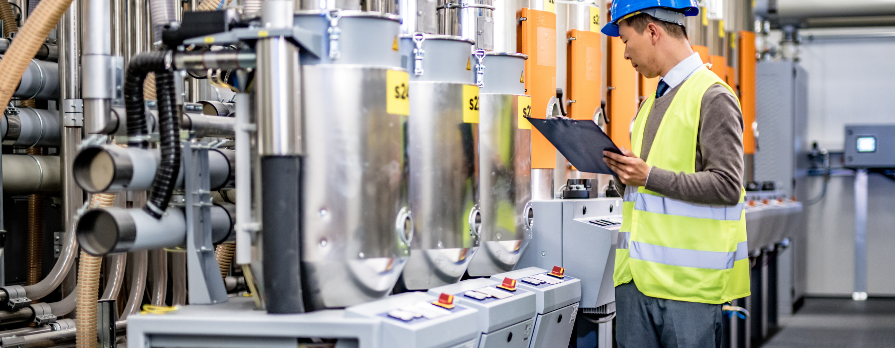 Engineer in safety gear inspecting industrial machinery in a modern factory, highlighting the need for Manufacturer Insurance.