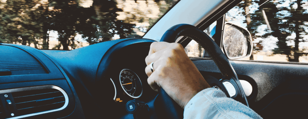 Close-up of a driver behind the wheel, illustrating comprehensive any driver insurance cover.