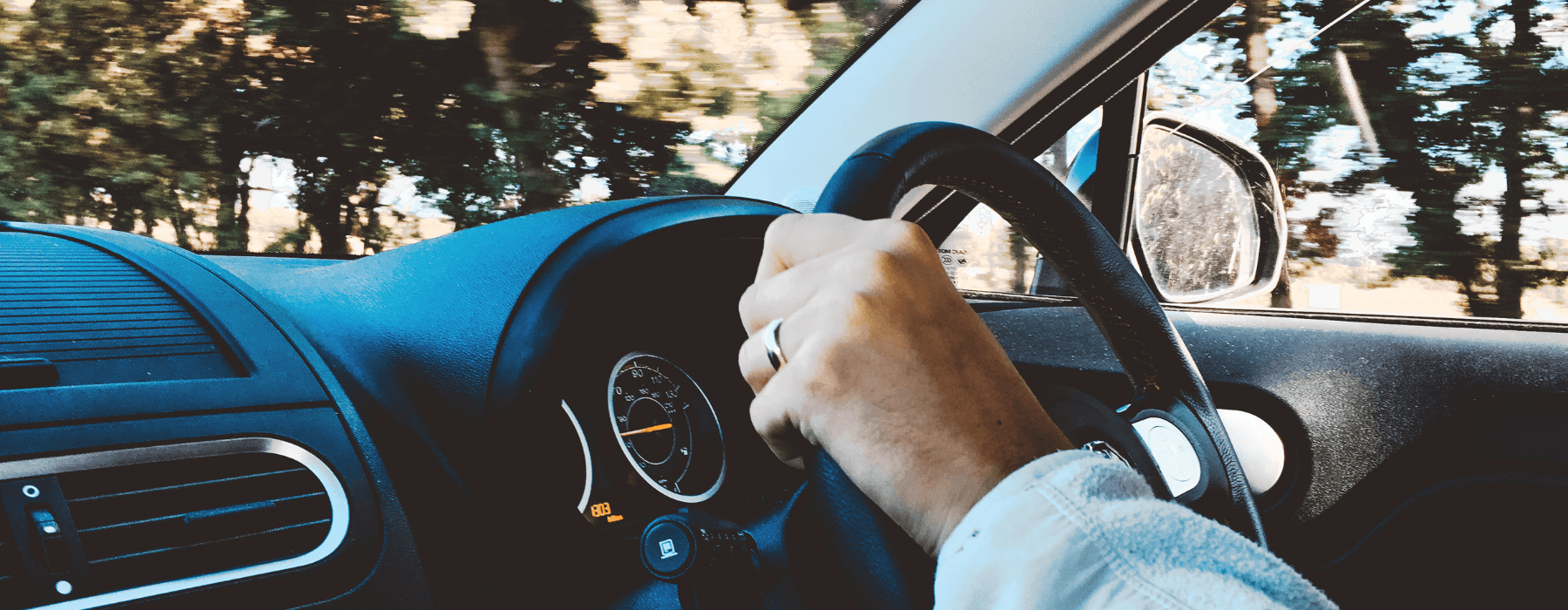 Close-up of a driver behind the wheel, illustrating comprehensive any driver insurance cover.