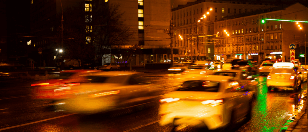 Night traffic in a busy UK city centre with blurred car lights and wet roads showing congestion and difficult driving conditions