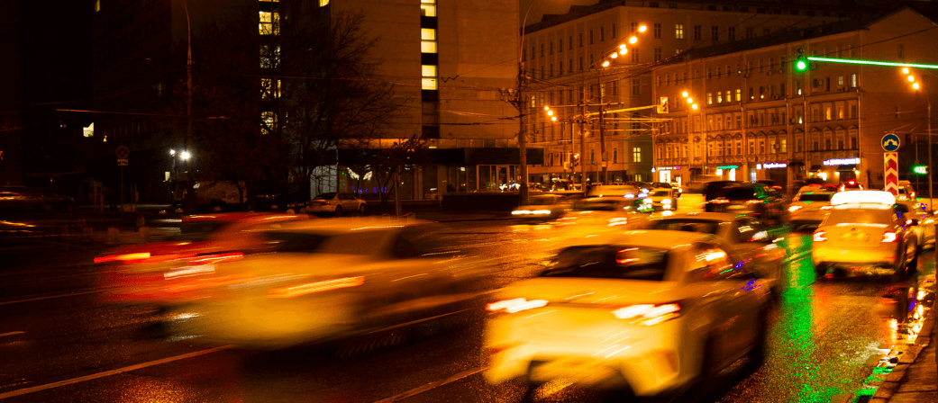 Night traffic in a busy UK city centre with blurred car lights and wet roads showing congestion and difficult driving conditions