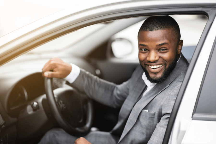 Business professional smiling while driving a car, representing comprehensive motor insurance