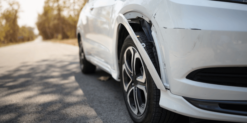 Close-up of damage to a car wheel arch after a road accident, representing vehicle insurance claims