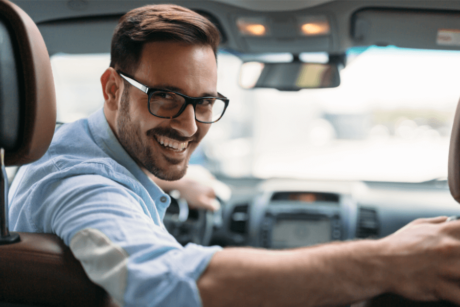 Smiling driver behind the wheel of a car, showing confidence and peace of mind with insurance cover