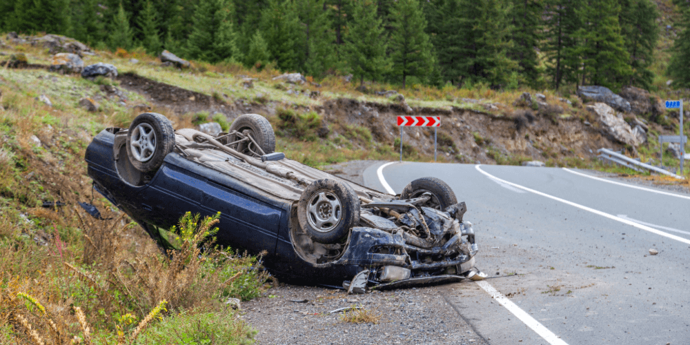 Overturned car on the side of a road after an accident, representing motor insurance claims and accident cover