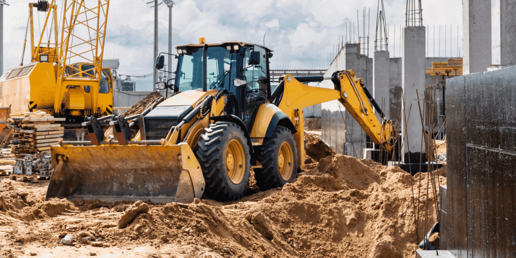 Backhoe loader moving soil during groundwork at a building construction site