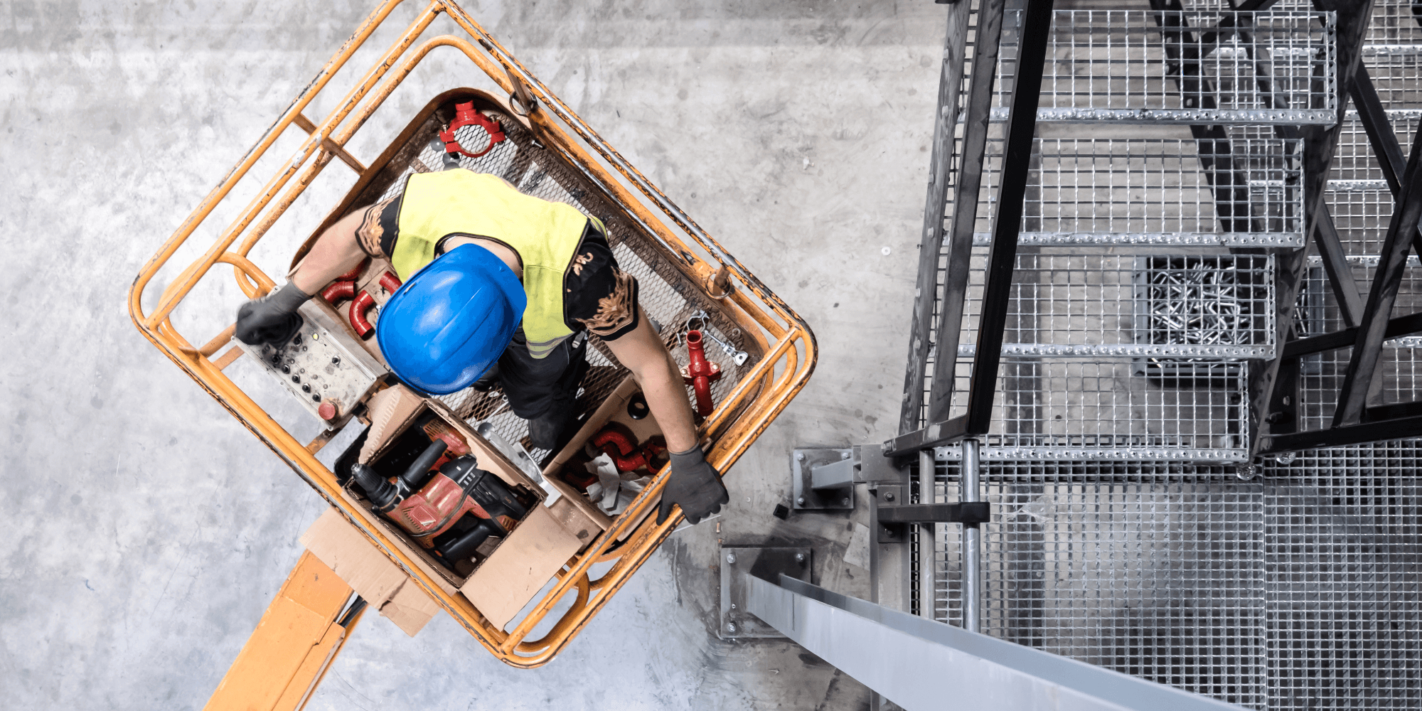 Construction worker operating insured access equipment from a cherry picker platform