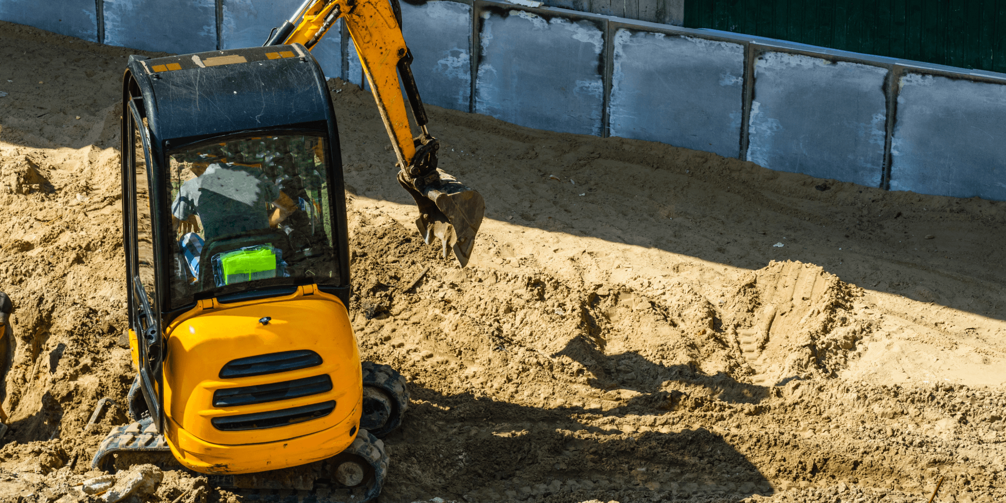 Compact excavator performing insured trenching and groundworks on a construction site