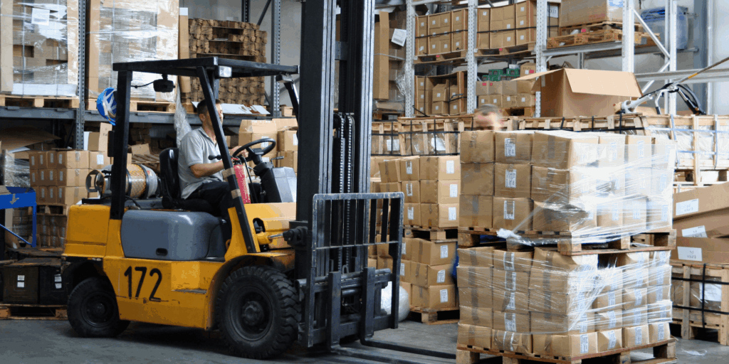Forklift moving shrink-wrapped pallets as part of insured warehouse and logistics operations