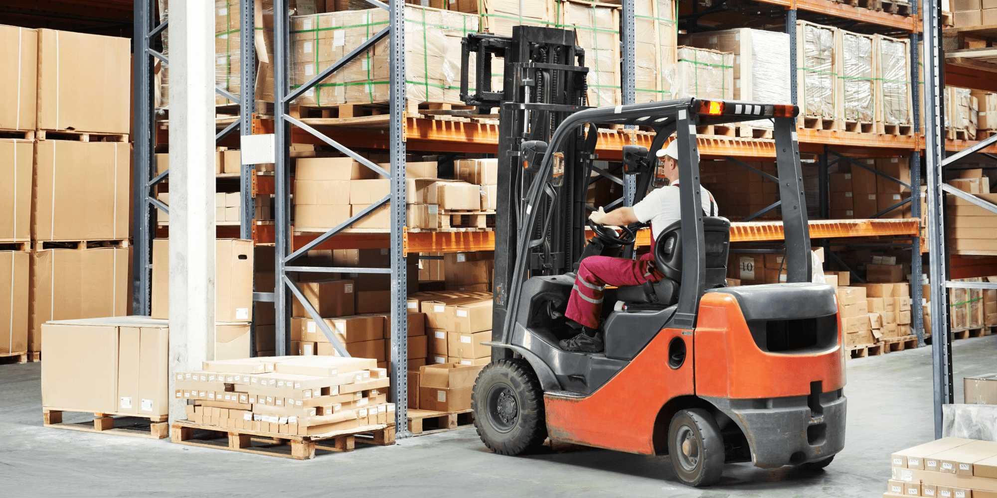 Forklift truck operating in a warehouse, handling palletised goods with insured plant equipment