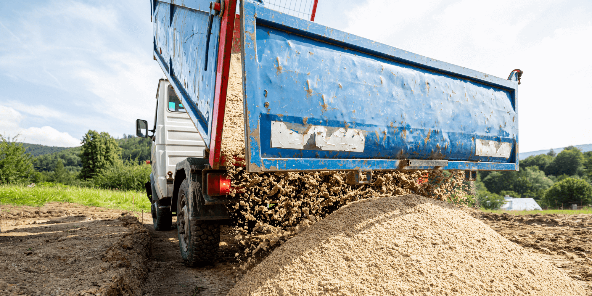 Tipper truck unloading aggregate on site during insured construction and haulage work