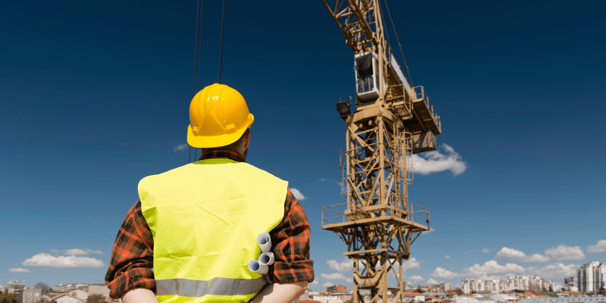 Construction supervisor overseeing insured tower crane operations on a building site