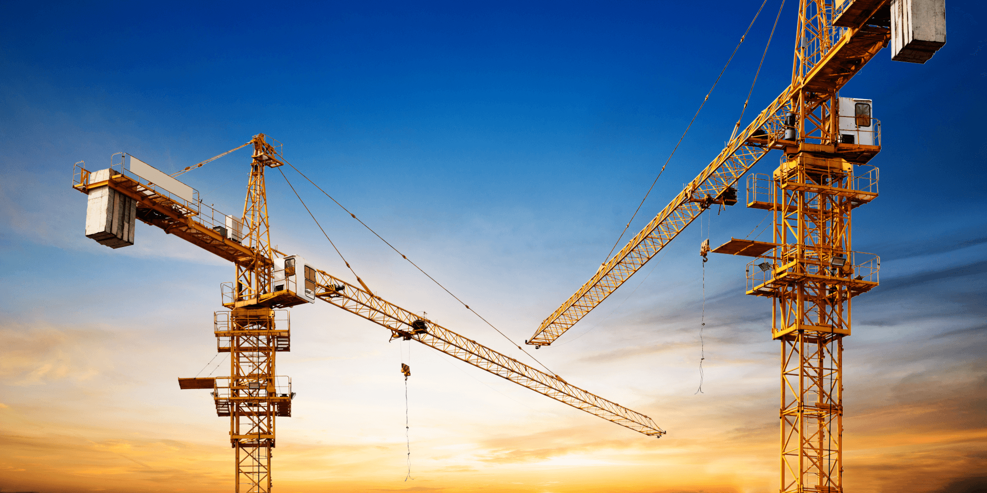 Tower cranes operating on a large construction site, representing insured lifting and plant equipment