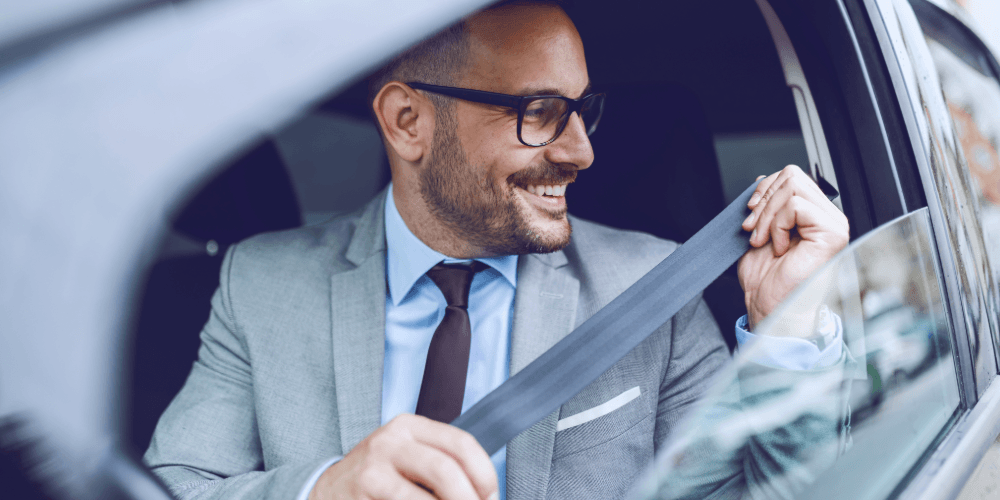 man putting his seatbelt on in a car with the window down